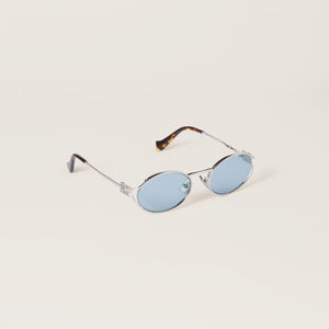 משקפי שמש מיו מיו אובליות מתכת כסופות עם הגנת UVA/UVB ורפידות אף מתכווננות.